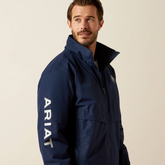Man wearing a navy blue Ariat jacket on a beige background